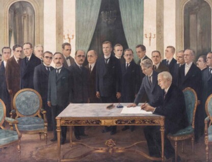 Pintura histórica de Gentil Garcez que retrata a solenidade de sanção do projeto de criação da Universidade de Minas Gerais (UMG). No centro da composição, o presidente do estado de Minas Gerais, Antônio Carlos de Andrada, está sentado à direita, assinando um documento sobre uma mesa nobre, de madeira trabalhada com detalhes dourados. Ao seu lado esquerdo, um secretário ou assessor escreve ou organiza papéis. Atrás deles, em pé, há um grupo de aproximadamente vinte homens, todos vestidos formalmente com ternos escuros e gravatas. As expressões são sérias e respeitosas, evidenciando a formalidade do momento. O ambiente é luxuoso: o salão tem paredes claras, grandes espelhos arqueados, poltronas estofadas em verde com acabamento dourado e pesadas cortinas verde-escuras ao fundo. Dois candelabros dourados com velas estão presos às paredes.
