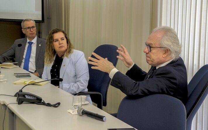 Imagem mostra, da esquerda para a direita, Manuel Palácios, Sandra Goulart e Alessandro Moreira, sentados em mesa durante reunião na Reitoria