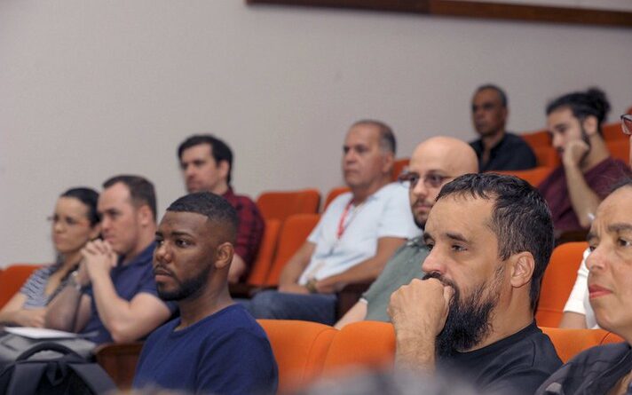 Imagem mostra diversas pessoas em auditório