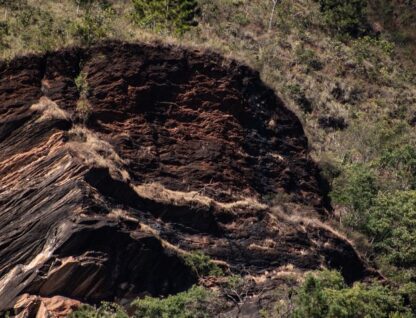 Imagem mostra terreno com formação rochosa em evidência e vegetação em volta