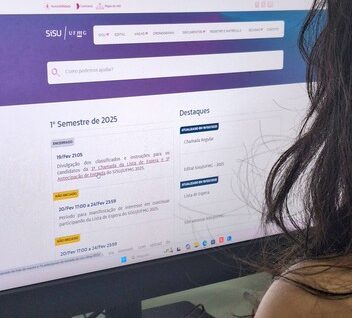 Imagem mostra vista por trás de pessoa mexendo em computador, em site Sisu UFMG