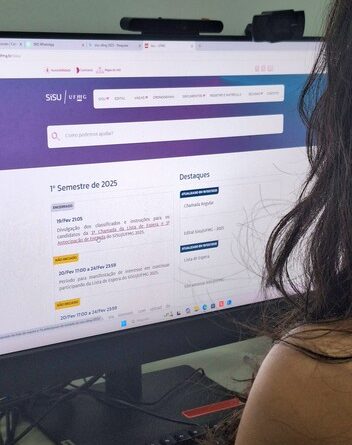 Imagem mostra vista por trás de pessoa mexendo em computador, em site Sisu UFMG