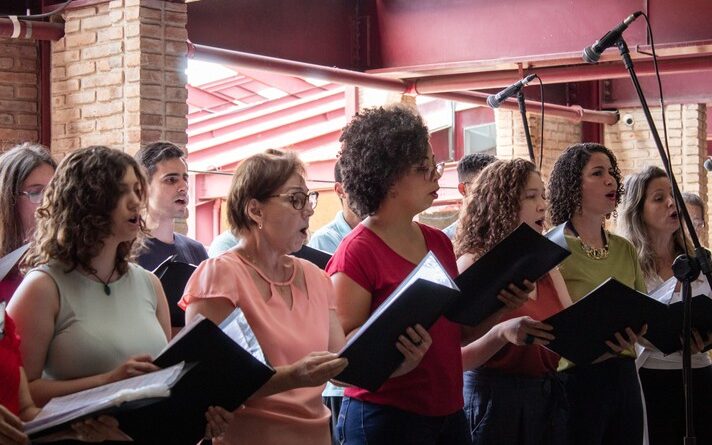 Imagem mostra coristas em apresentação na praça de serviços do campus Pampulha da UFMG