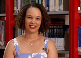 Mulher negra com cabelos crespos acima dos ombros, usa blusa azul com elementos brancos