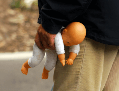 Mão segurando uma boneca de plástico