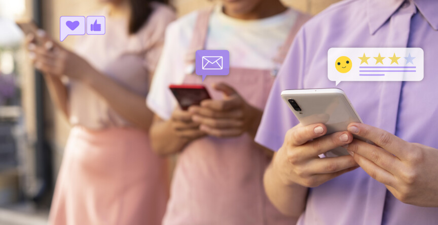 Três jovens, vestidos em tons de rosa e roxo, com celulares nas mãos. Sobre os aparelhos estão ícones de mensagem, coração, emoji e estrelas
