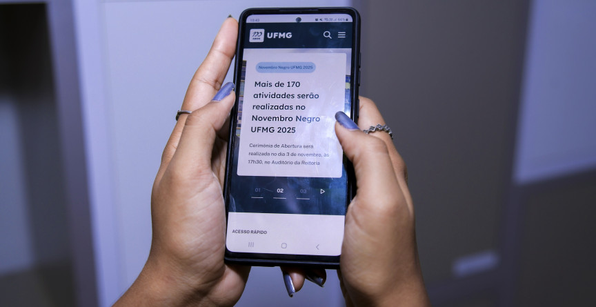 Usuária segura com as duas mãos um celular que exibe conteúdo novo portal da UFMG