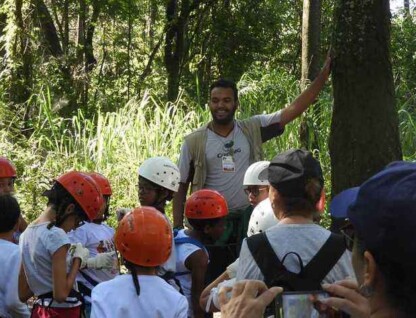 Instrutor conversa com crianças em área arborizada