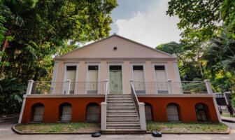 Prédio em tons rosa construído em área arborizada