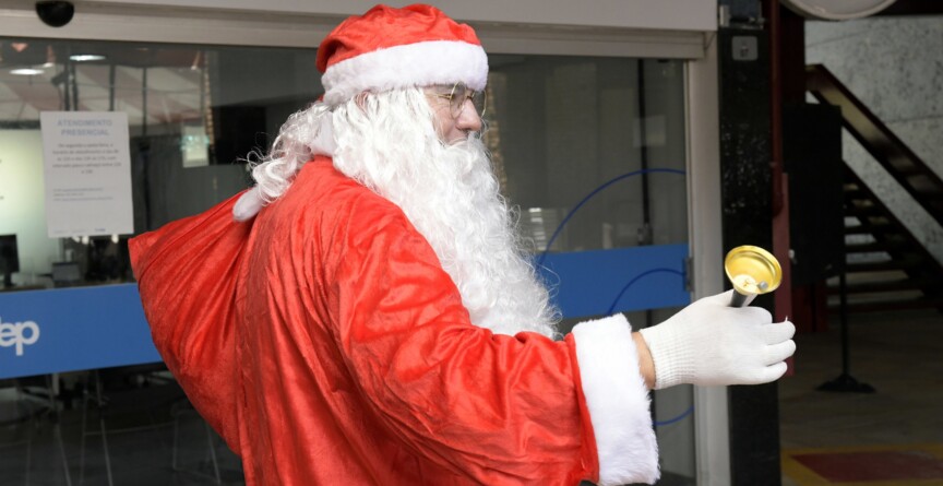 Homem vestido de roupa vermelha caracterizado como Papai Noel circula na Praça de Serviços