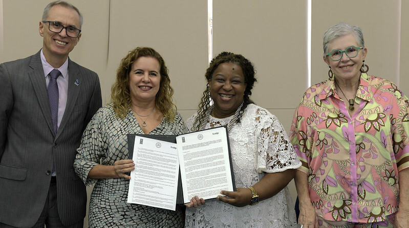 A reitora da UFMG, Sandra Goulart, e a ministra Macaé Evaristo exibem a carta-acordo, ao centro, ladeados pelo vice-reitor Alessandro Fernandes e pela Secretária Nacional dos Direitos da Criança e do Adolescente, Pilar Lacerda