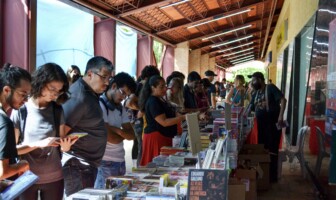 Pessoas olham para livros nas bancas das editoras durante edição da Festa do Livro UFMG