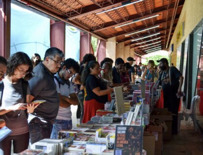 Pessoas olham para livros nas bancas das editoras durante edição da Festa do Livro UFMG