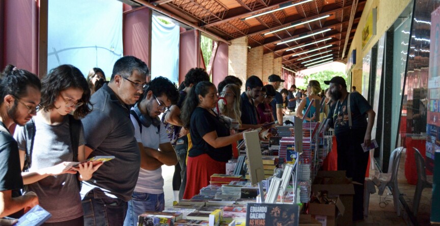 Pessoas olham para livros nas bancas das editoras durante edição da Festa do Livro UFMG