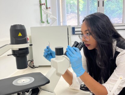 Pesquisadora Nathalia Oliveira, da Faculdade de Farmácia, manipula lâminas de vidro junto a um microscópio
