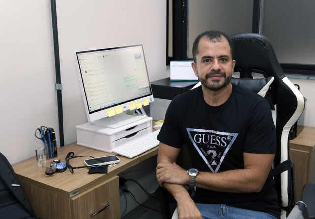Professor Flaviano dos Santos Martins à direita de um computador