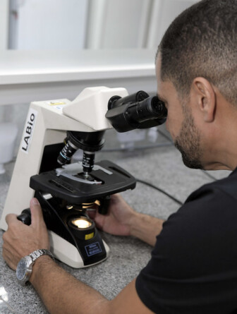 Professor Flaviano dos Santos Martins observa uma amostra em um microscópio