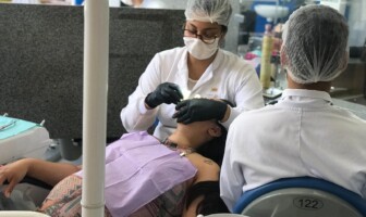 Duas dentistas realizam atendimento odontológico a uma gestante.