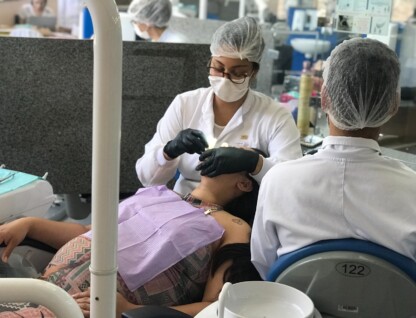 Duas dentistas realizam atendimento odontológico a uma gestante.
