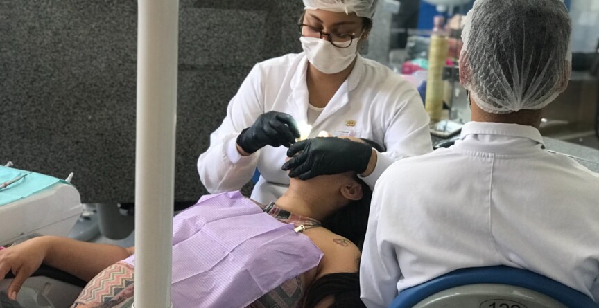 Duas dentistas realizam atendimento odontológico a uma gestante.