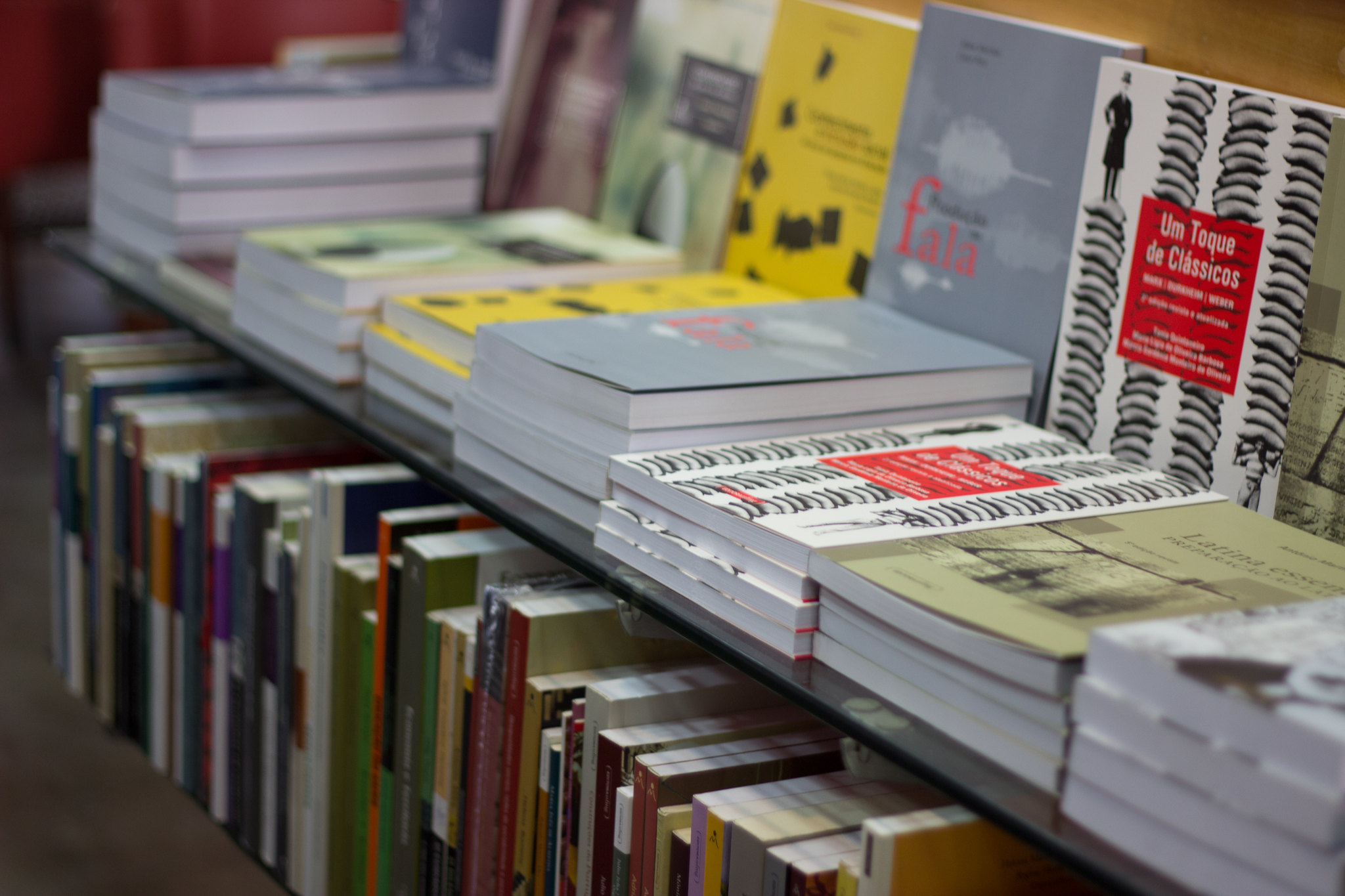 Prateleiras de vidro com livros empilhados na livraria UFMG
