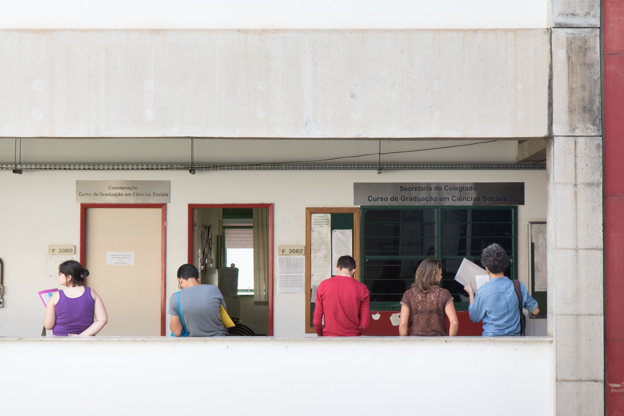 alunos apoiados na meia parede no prédio da fafich aguardando atendimento do colegiado e coordenação do curso de ciências sociais.