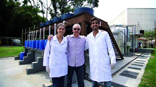 Professor Carlos Chernicharo, orientador do trabalho, entre os estudantes Catarina Azevedo e Augusto de Assis Temponi; ao fundo, a planta de metanização