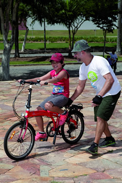 Voluntário do Bike Anjo orienta criança em sua bicicleta